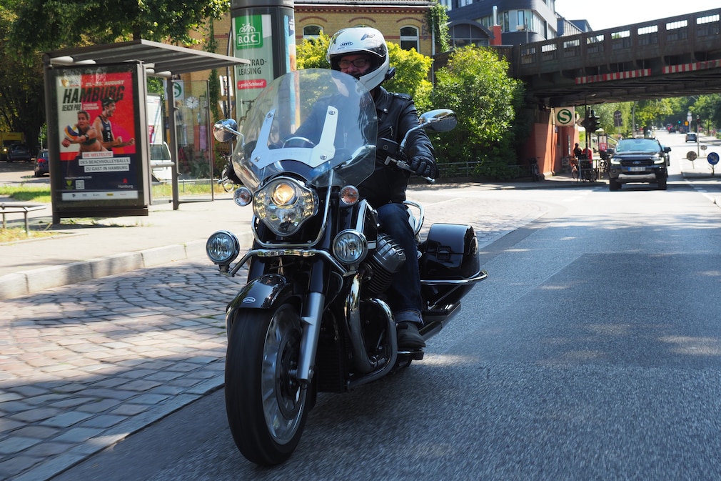 Ein Motorrad schräg von vorn im Strassenverkehr. Am Helm des Fahrers ist deutlich sichtbar ein Headset angebracht.