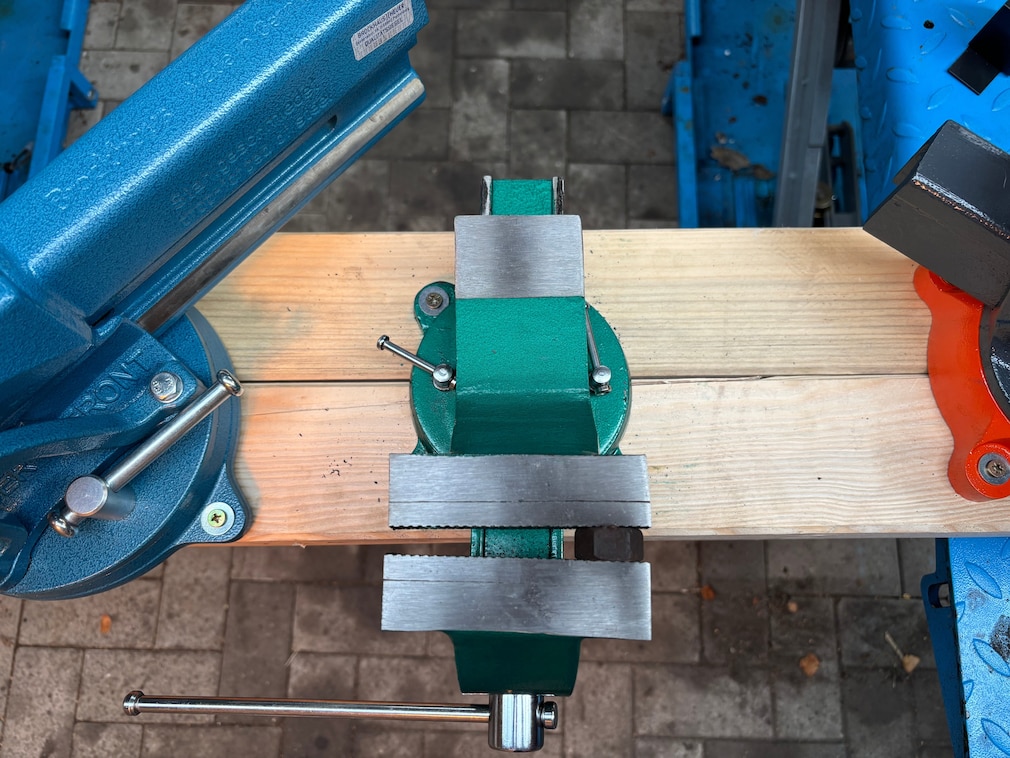 Draufsicht eines Schraubstocks, in den ein Gegenstand einseitig eingespannt ist, um die Verwindung zu demonstrieren und die Bruchsicherheit zu testen.