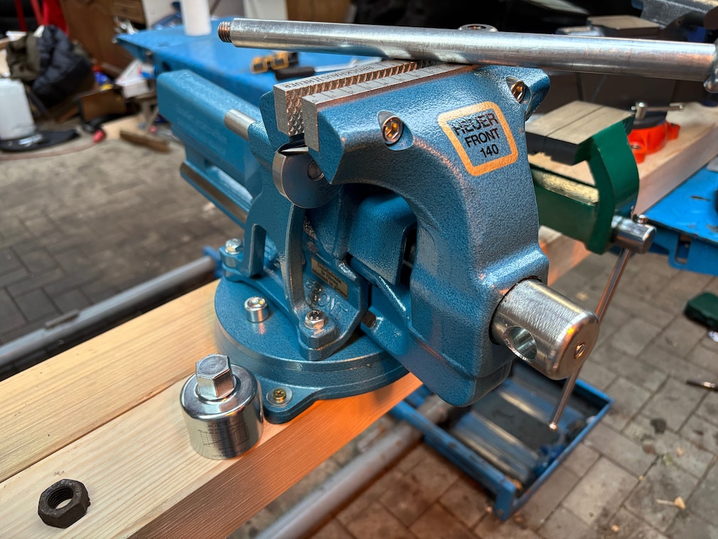 Nahaufnahme des Heuer-Schraubstocks von der Seite mit Blick auf den demontierten Spindelschlüssel und den Sechskantaufsatz in Werkstattumgebung.