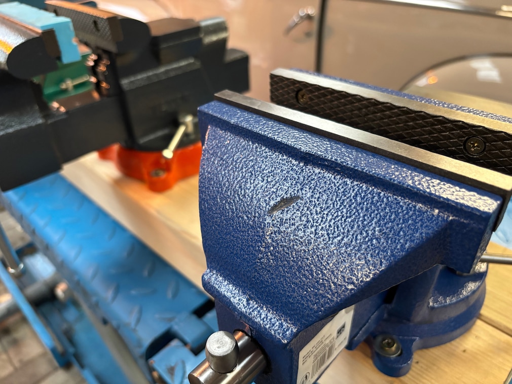 Testsituation: Nahaufnahme der beschädigten Beschichtung eine Schraubstocks nach Belastungstest.