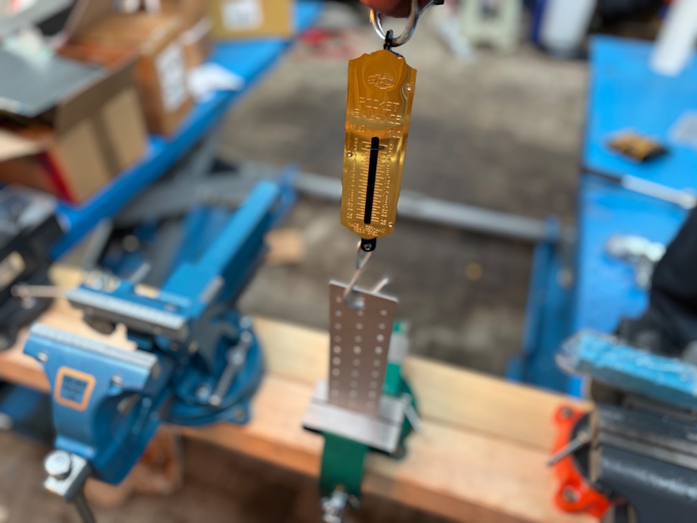 Testsituation: Zugwaage, verbunden mit einem in einem Schraubstock festgeklemmten Blech. Daneben weitere aufgereihte Schraubstöcke.