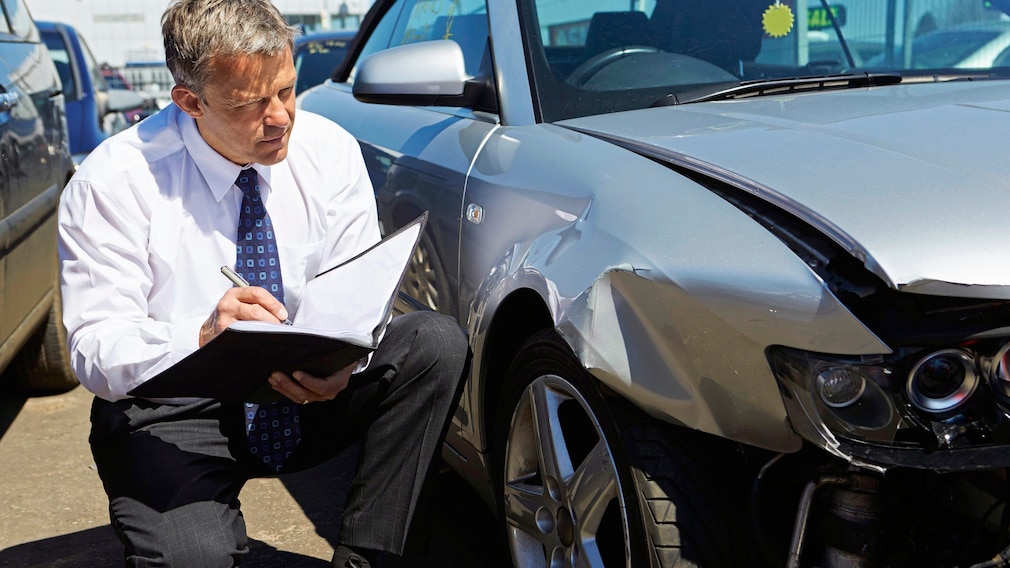 Loss Adjuster Inspecting Car Involved In Accident