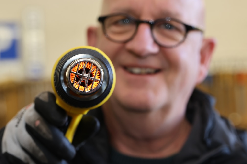 Redakteur hält angeschaltete Heißluftpistole in die Kamera