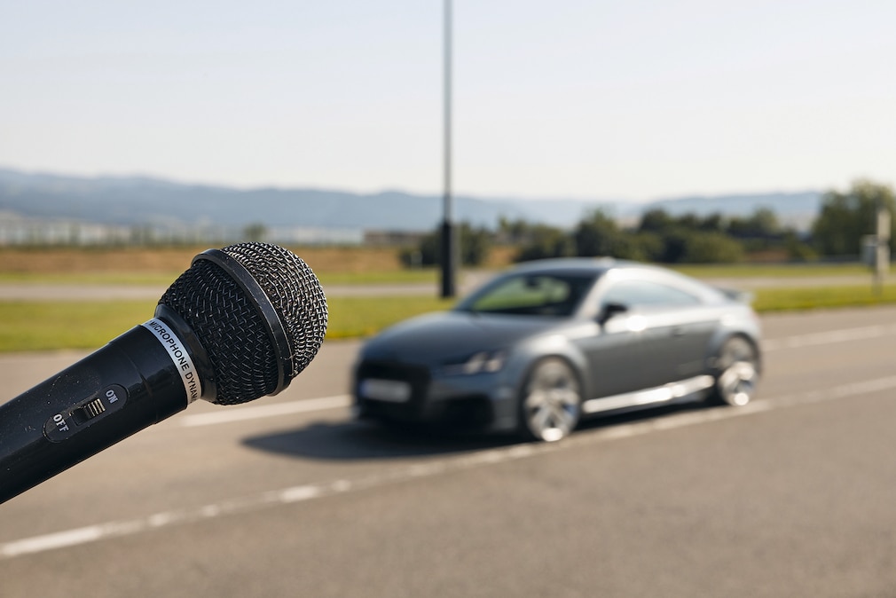 Mikrofon, im Hintergrund unscharf ein Audi TT