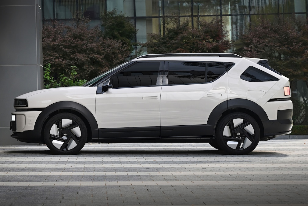 Hyundai Nexo steht in Seitenansicht vor moderner Glasfassade.