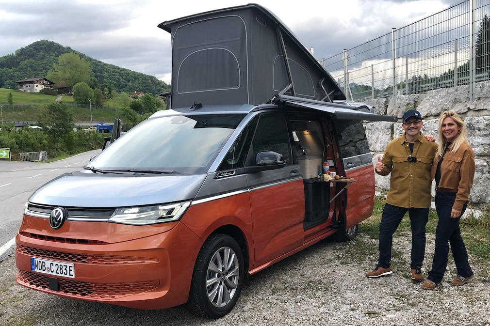 VW Multivan mit hochgeklapptem Aufstelldach und Pärchen neben dem Auto