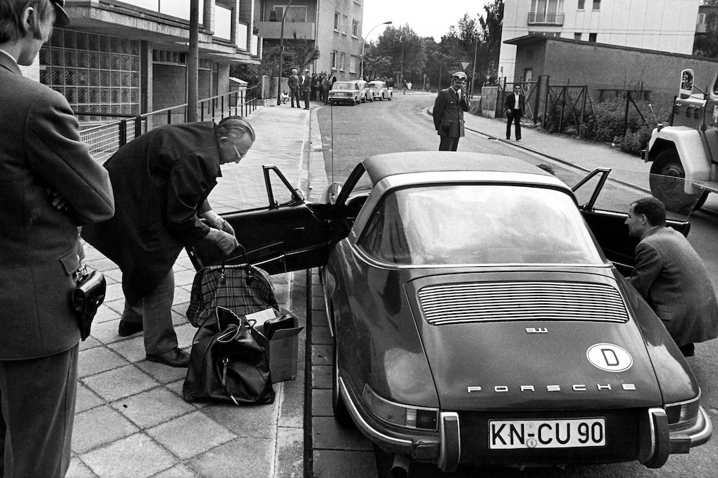 Schwarzweißfoto mit dem Porsche 911 Targa mit offener Fahrertür, mit Polizisten und mutmaßlichen Zivilbeamten