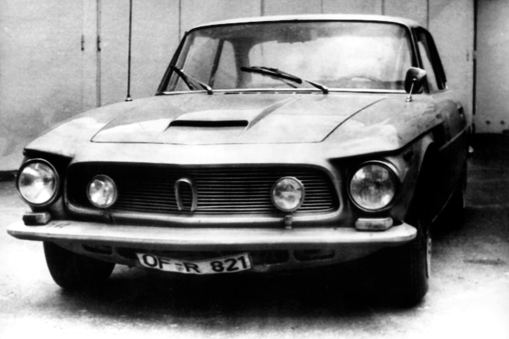 Schwarzweißfoto von einem Iso Rivolta 300 oder GT von vorn mit verbogenem DIN-Kennzeichen