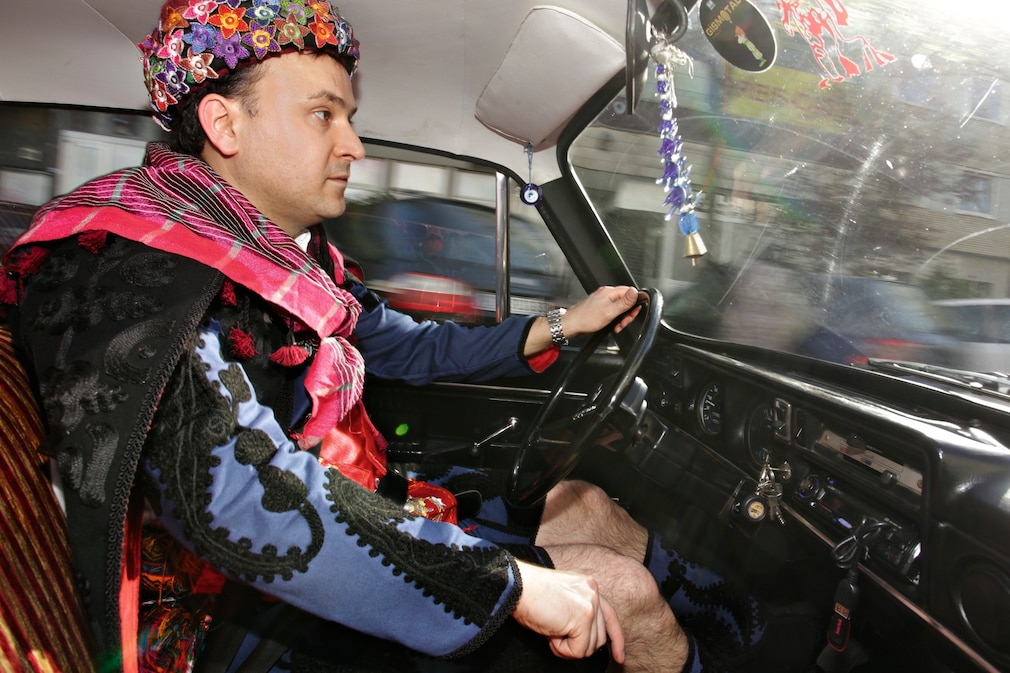 Mann in türkischer Tracht fahrend am Steuer des Anadol A2