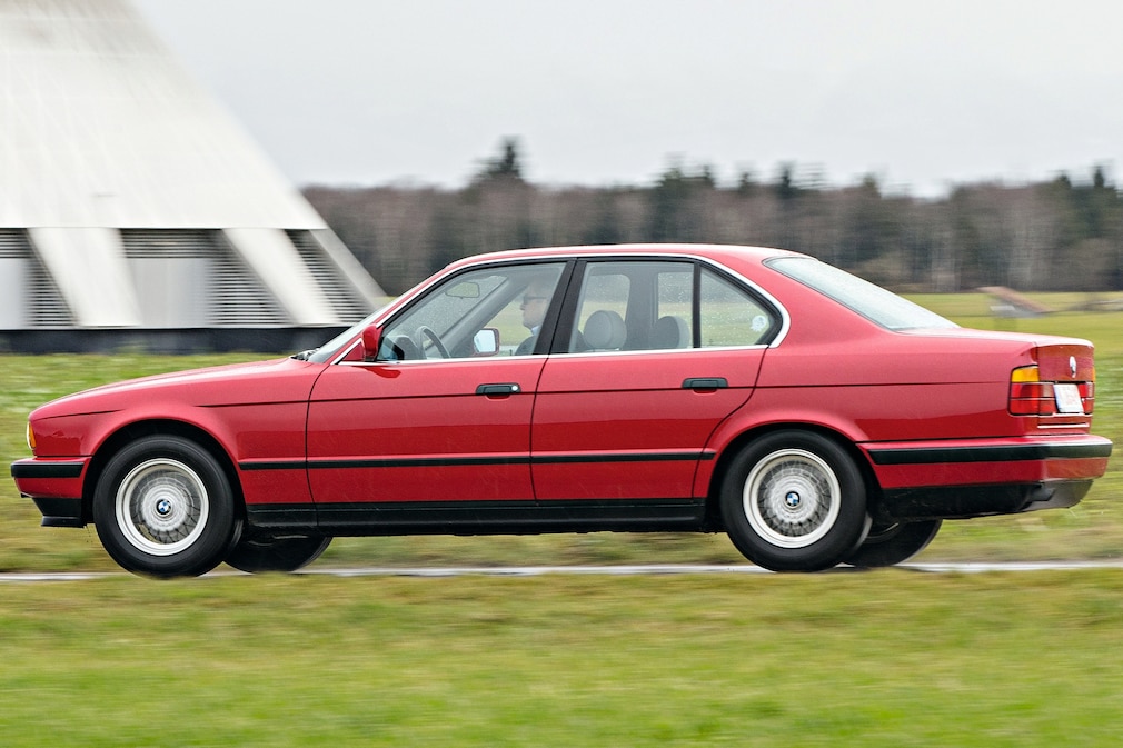 BMW Fünfer E34 fahrend von der Seite, leicht von hinten