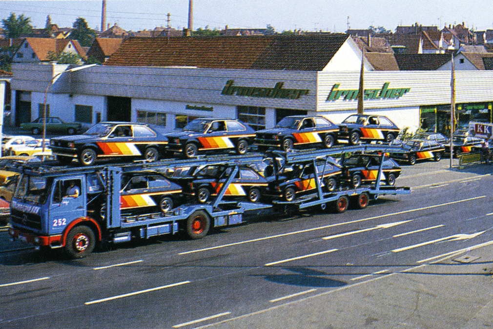 Autotransporter vollbeladen mit gleich aussehenden Opel Kadett C City vorm Firmengebäude von Irmscher