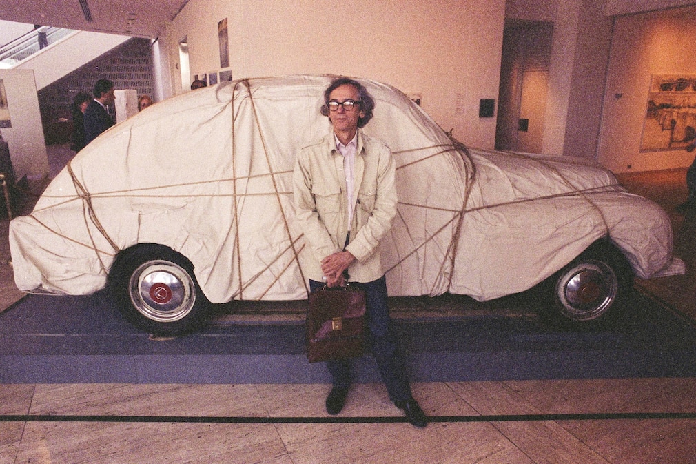 Christo steht am verhüllten Buckelvolvo