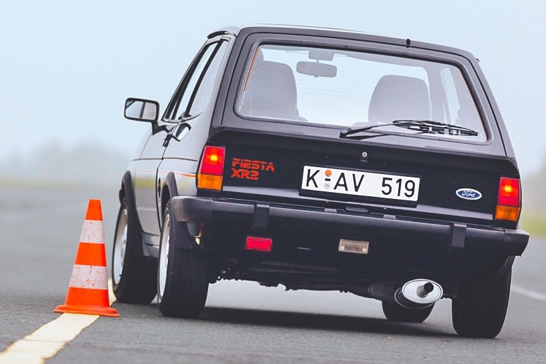 Schwarzer Ford Fiesta XR2 fahrend von hinten im Slalom