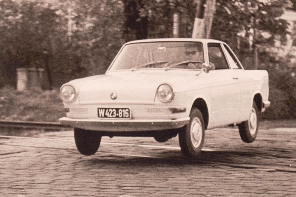 Historisches Schwarzweißfoto, BMW 700 über Bahnübergang springend, schräg von vorn
