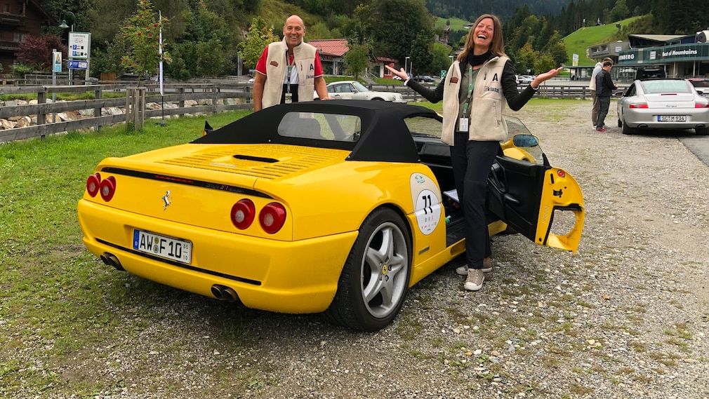 Gelber Ferrari F355 F1 Spider stehend von schräg hinten mit ihren Besitzern