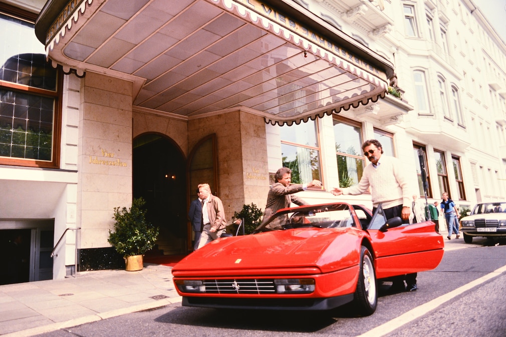 Historisches Farbfoto: Vorm Hamburger Luxushotel Vier Jahreszeiten übergibt Ferrari-Händler Thomas Wichelhausen seinem Kunden Ion Tiriac den Ferrari 328 GTS.