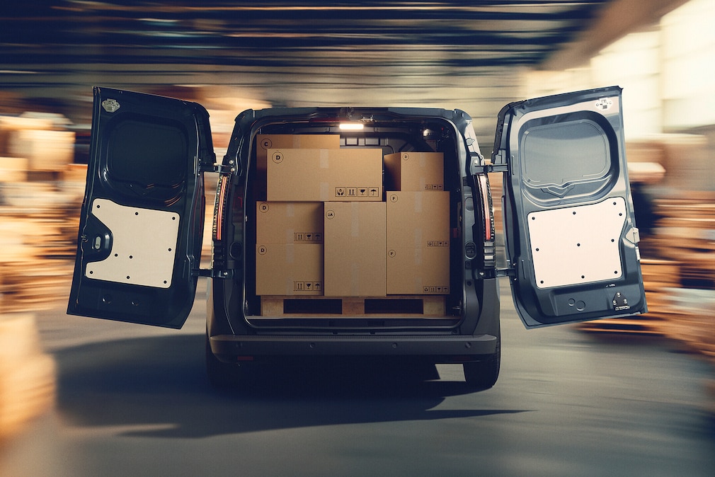 Mit Kartons vollgepackter Renault Trafic E-Tech Electric mit offenen Hecktüren.
