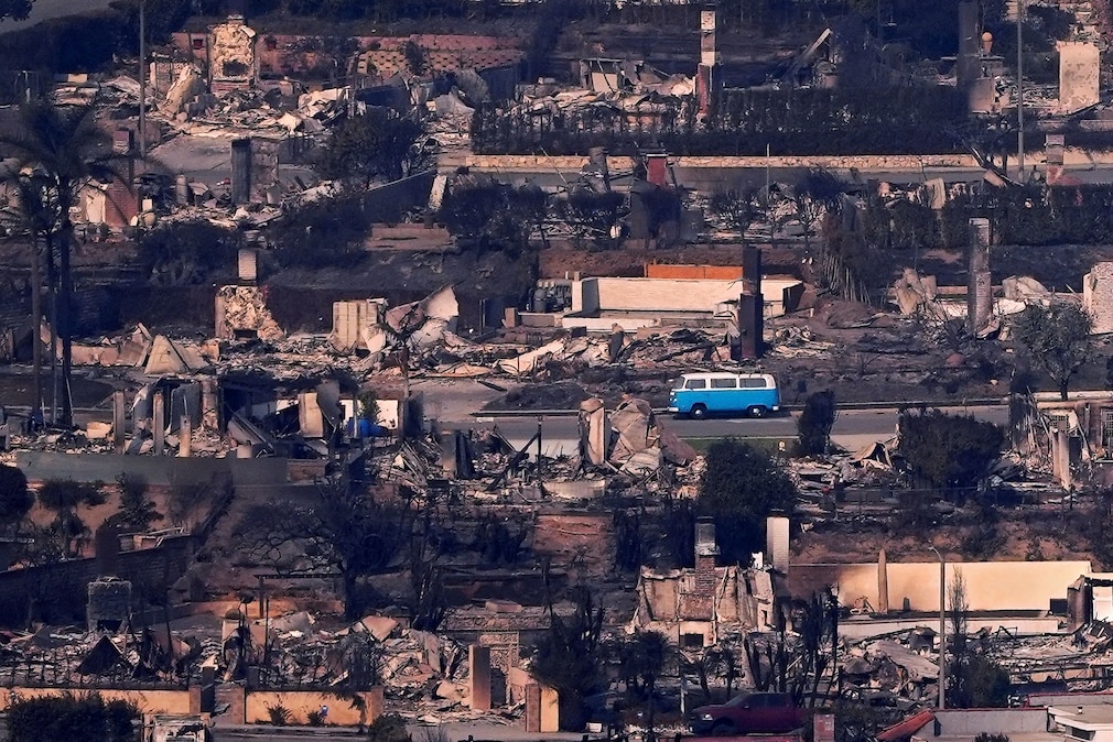 Blauer VW T2 von der Seite inmitten einer Ortschaft nach einem Großfeuer