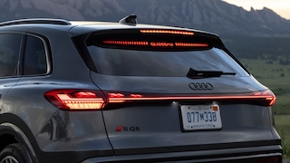 Heckansicht eines Audi SQ5 mit leuchtendem quattro-Schriftzug bei Sonnenuntergang.