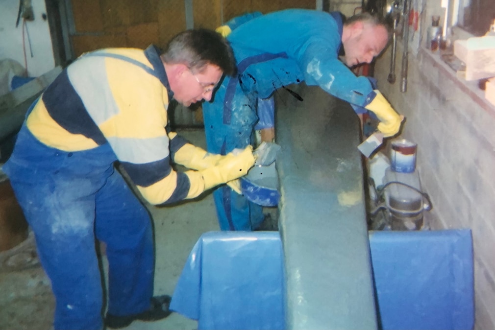 Zwei Handwerker laminieren in einer Garage eine Tragfläche