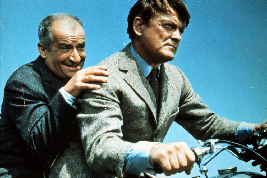 historische Filmszene: Louis de Fenès und Jean Marais sitzen hintereinander auf einem fahrenden Motorrad