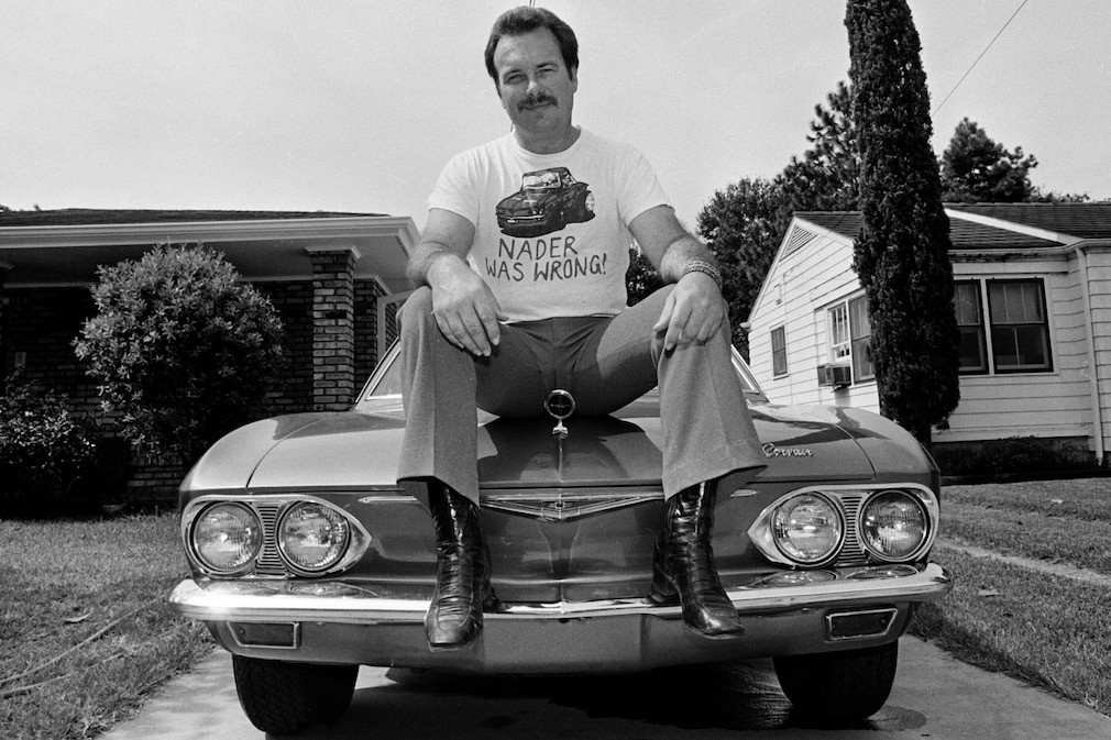historisches Schwarzweißfoto, Mann sitzt auf der Motorhaube seines Chevrolet Corvair