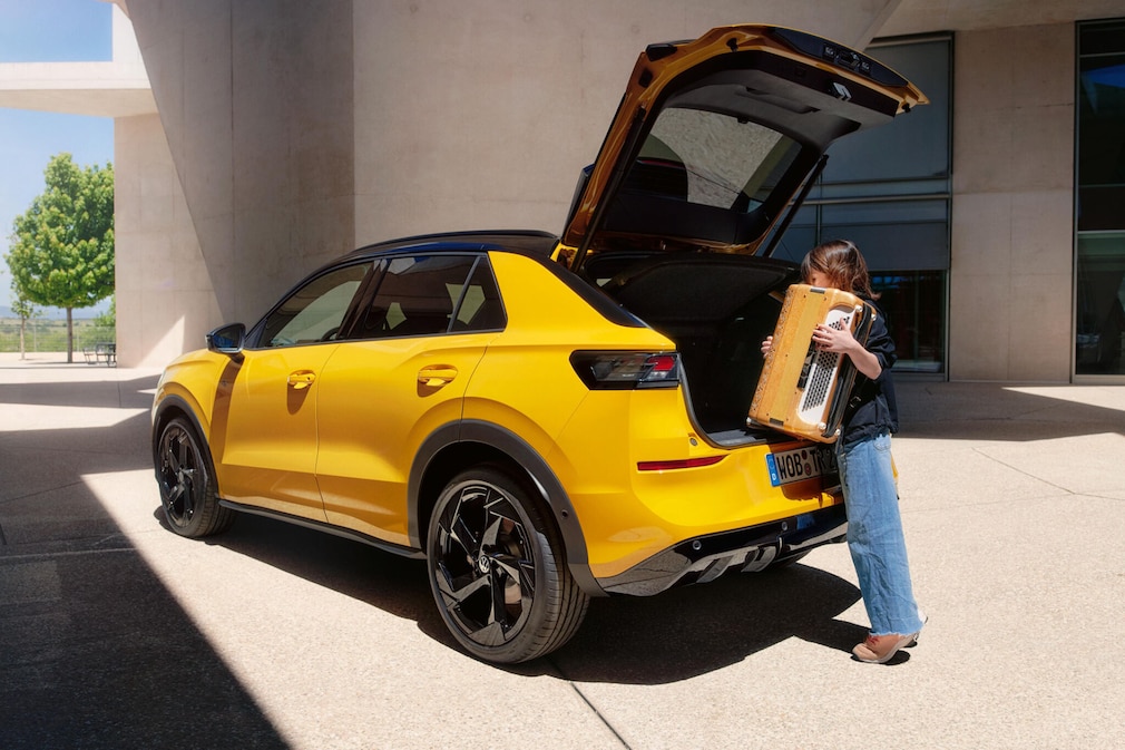 Mann packt ein großes Paket in den Kofferraum des T-Roc