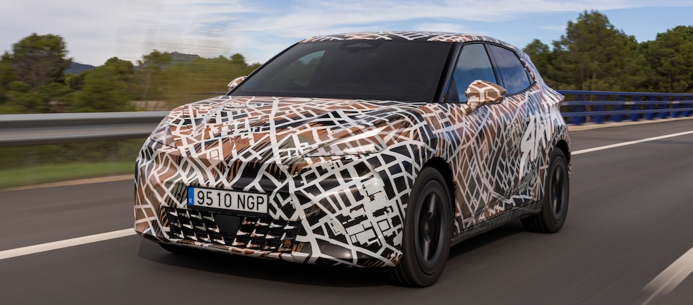 Getarnter Cupra Raval fährt auf einer Landstraße.