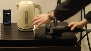 Ein Wasserkocher wird mit einem Adapter an den großen Stecker einer Wallbox verbunden