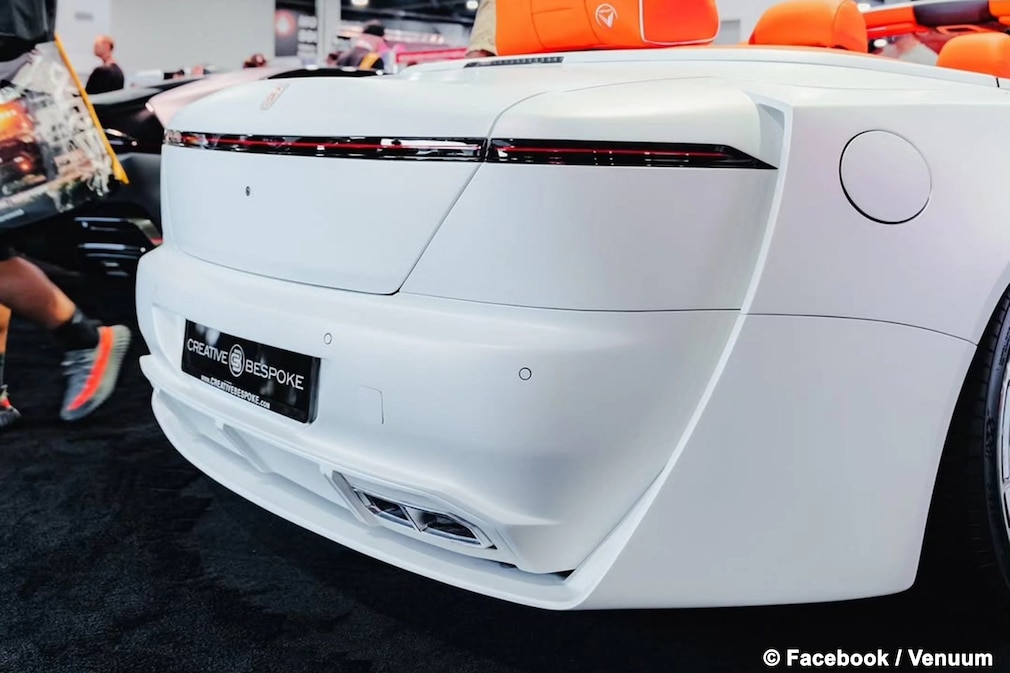 Heck eines weißen Rolls-Royce Dawn als Custom-Umbau mit orangem Interieur auf einer Messe.