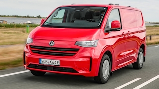 Roter VW Elektro-Transporter fährt auf einer Landstraße am Wasser.