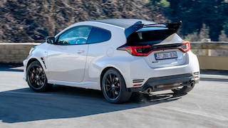 Toyota GR Yaris fährt schräg von hinten über eine kurvige Straße.