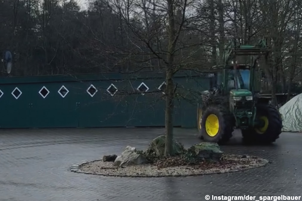 John Deere-Traktor beim Driften auf einem gepflasterten Hof.