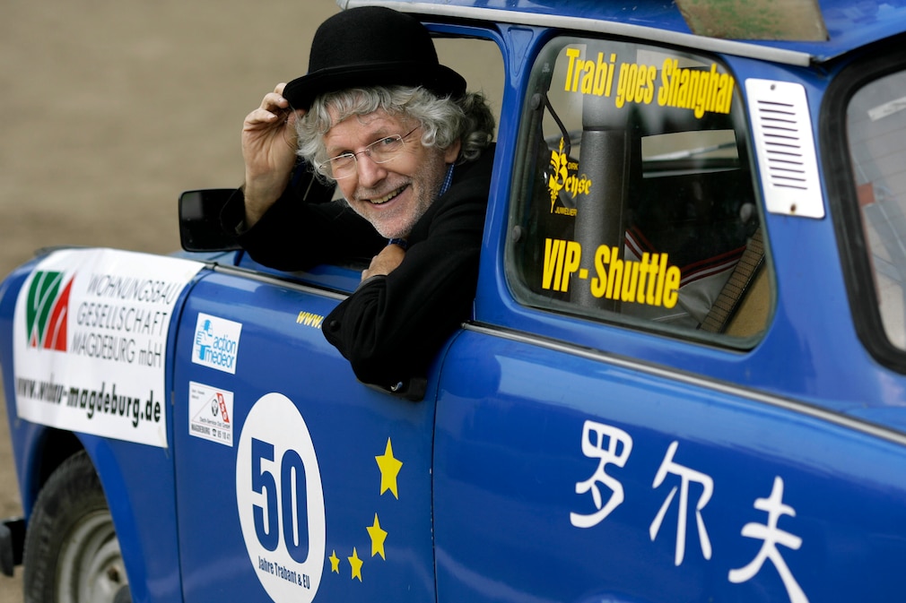 Mann mit Hut lehnt sich aus Fahrerfenster eines blauen Trabant 601