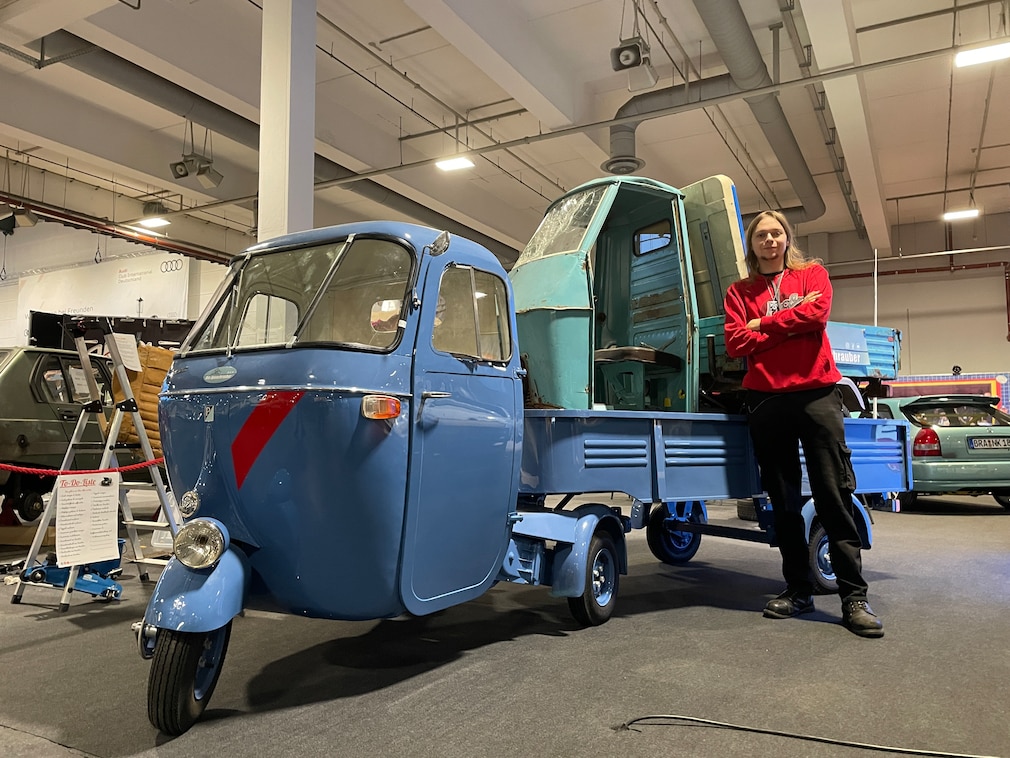 Mann lehnt an seiner blauen Sattelzug-Piaggio Ape. Auf der Ladefläche steht eine weitere, verunfallte Ape.
