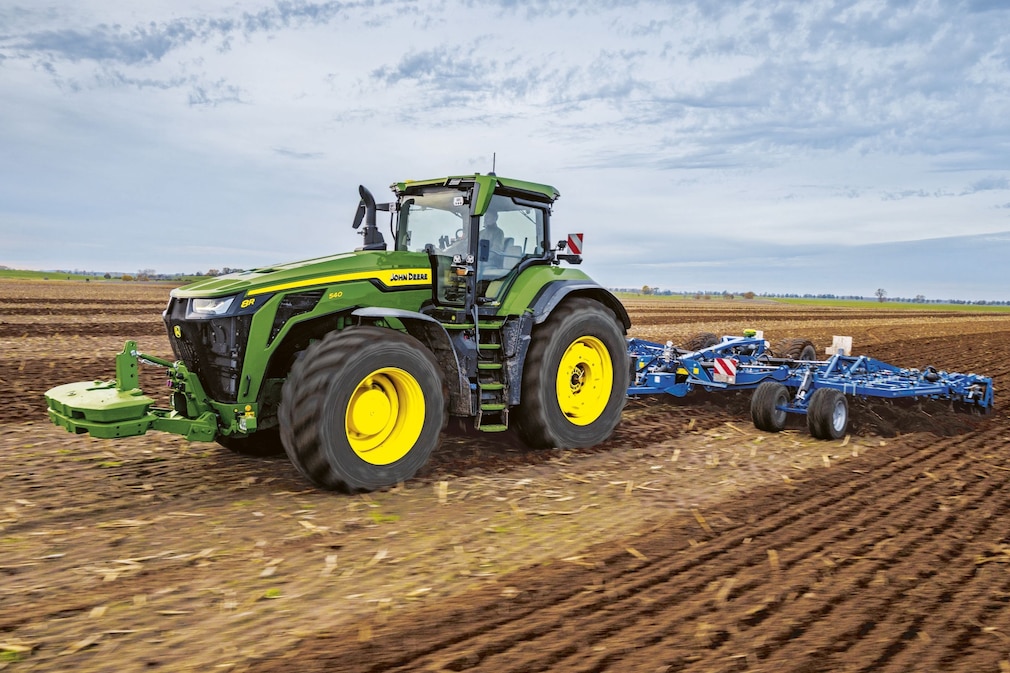 John Deere 8R Traktor bei der Bodenbearbeitung auf einem Acker.