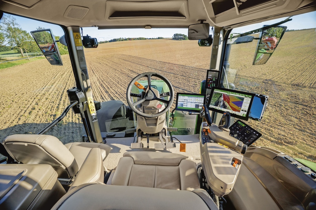 John Deere 8R Traktor mit digitalem Cockpit und Blick über ein Feld.