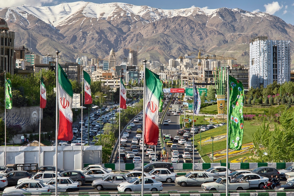 Stra0enszene in Teheran, vorn eine Straßenbrpücke, im Hintergrund Gebirge