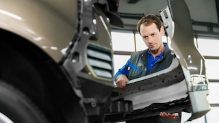 Mechaniker montiert eine Stoßstange an einem Ford-Fahrzeug in der Werkstatt.