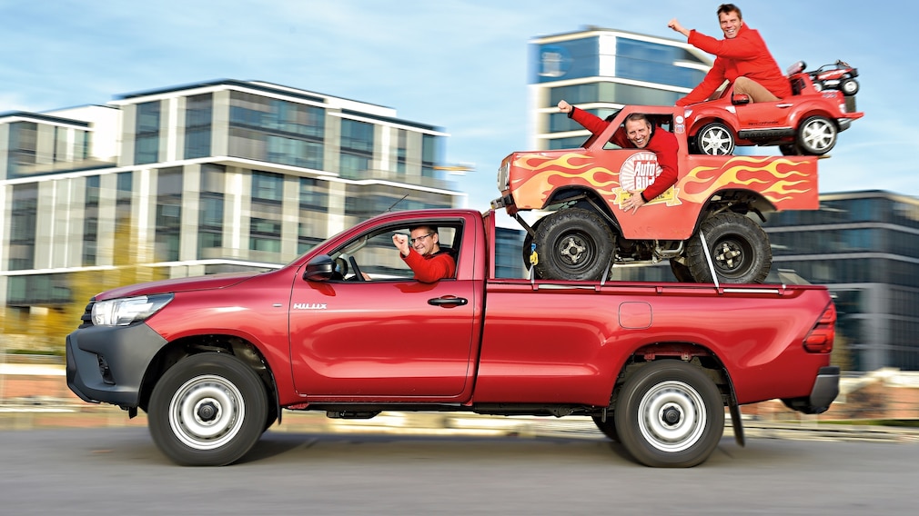 Vier Pick-ups übereinander gestapelt: Toyota Hilux, AUTO BILD- Minimonstertruck, Kinder-Elektromobil "Ford Raptor" und RC-Car "Razor"