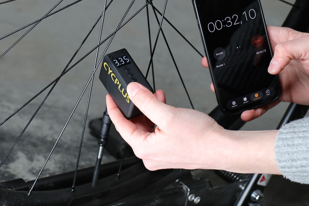 Die Cycplus-Pumpe füllt den Reifen während die Zeit mit dem Handy gestoppt wird.