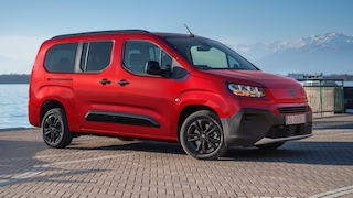 Fiat Doblò rot seitlich am Seeufer mit Bergpanorama.