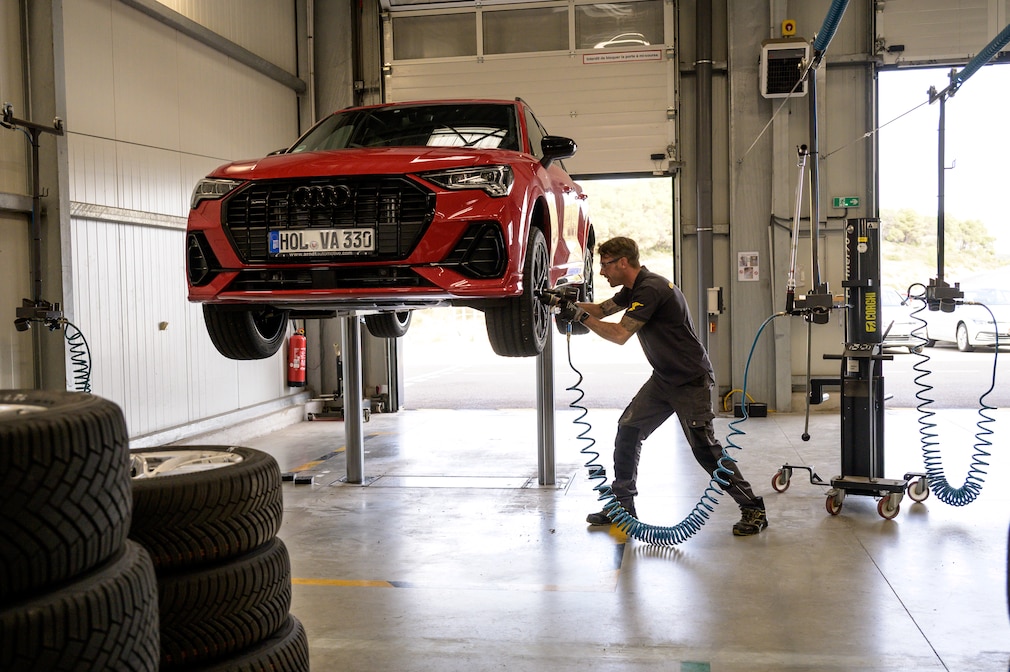 Ein Mechaniker montiert das vordere linke Rad des Testwagens, der auf einer Hebebühne steht