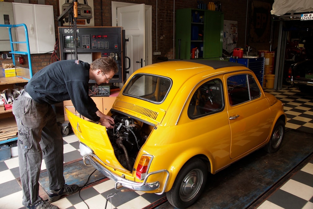 Fiat Nuova 500 (Fiat 500 Oldtimer) mit offeneer Motorhaube, jemand steht dahinter.