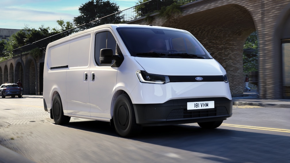 Weißer Ford Transit City Van fährt durch eine Stadtstraße mit Backsteinarkaden.