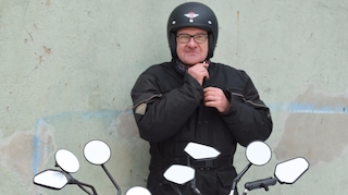 Aufmacherbild Motorradspiegel-Test: Alle Testspiegel am Motorradlenker befestigt, Tester im Hintergrund.