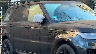 Range Rover mit Seitenspiegel in einem hellblauen Beutel parkt in einem Wohnviertel an der Straße.