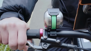 Detailaufnahme eines Fahrradlenkers mit Skoda-Klingel während der Fahrt.