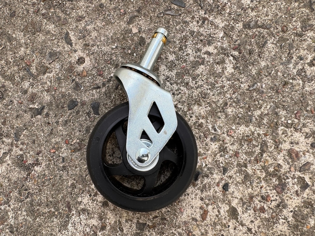 Nahaufnahme einer einzelnen Rolle mit Metallhalterung und Steckstift auf einem Betonboden.