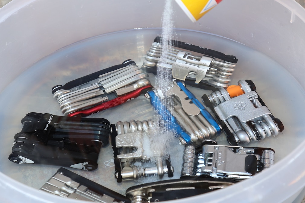 Die Multitools im Wasser in einer Schüssel während Salz von oben hereingekippt wird.